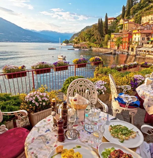 A meal laid out on a table on a balcony, with the view of the water in Bellagio, Lake Como