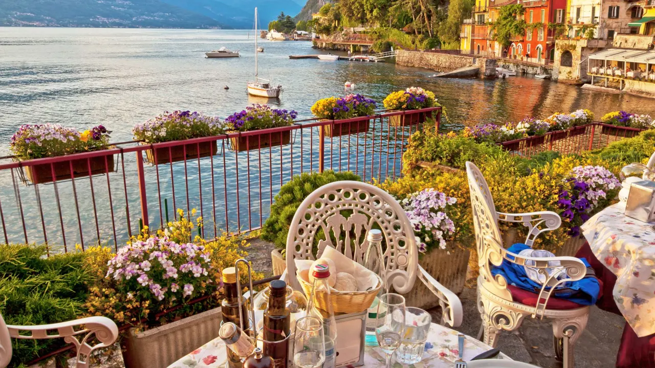 A meal laid out on a table on a balcony, with the view of the water in Bellagio, Lake Como