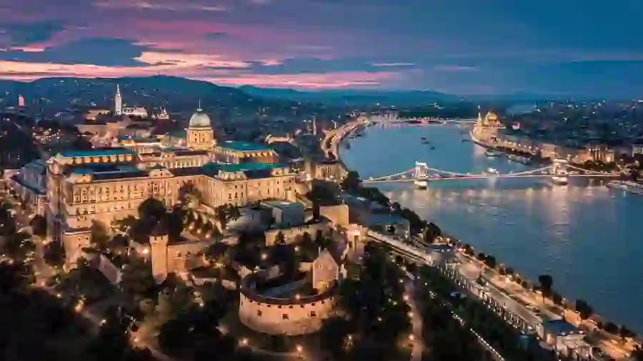 High angle view of the city of Pest at night time, showing its lit up buildings, the Danube river, and some of Pest