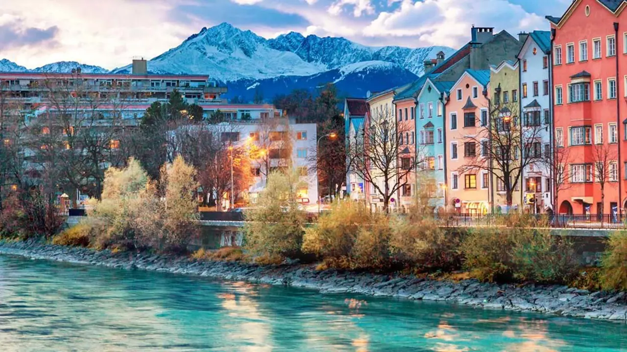 Buildings on the waterfront in Innsbruck, Austria with snowy mountains in the background