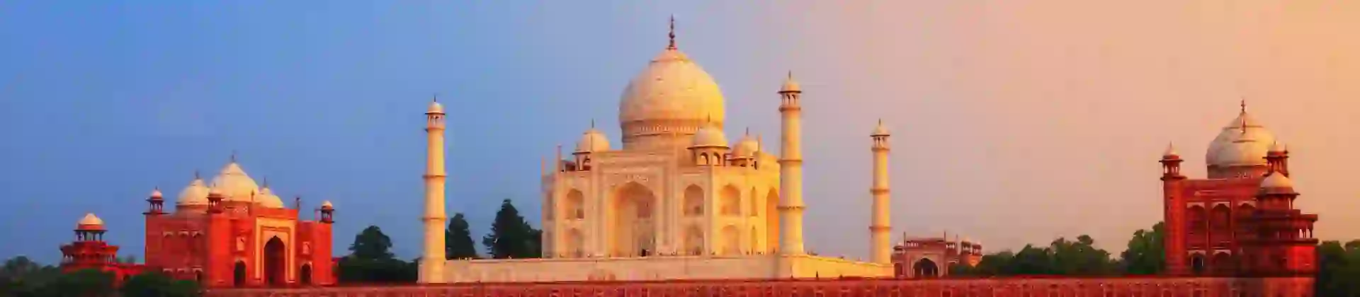 The Taj Mahal in Agra reflected in the calm waters of the Yamuna River at sunset
