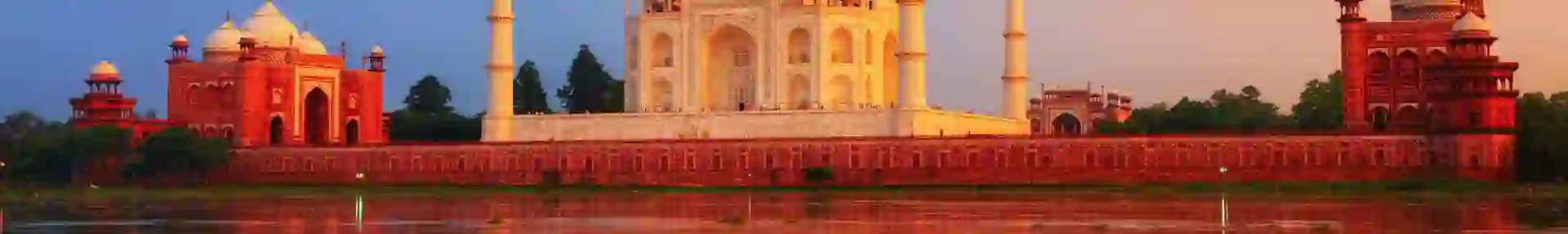 The Taj Mahal in Agra reflected in the calm waters of the Yamuna River at sunset