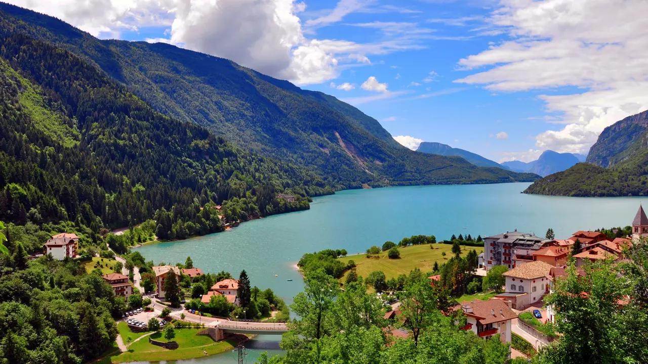 Shot of Molveno Lake in Italy, with buildings in the forefront and mountains 