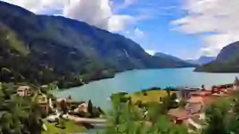 Molveno Lake in Italy, with colourful houses in the foreground and rolling hills alongside the lake