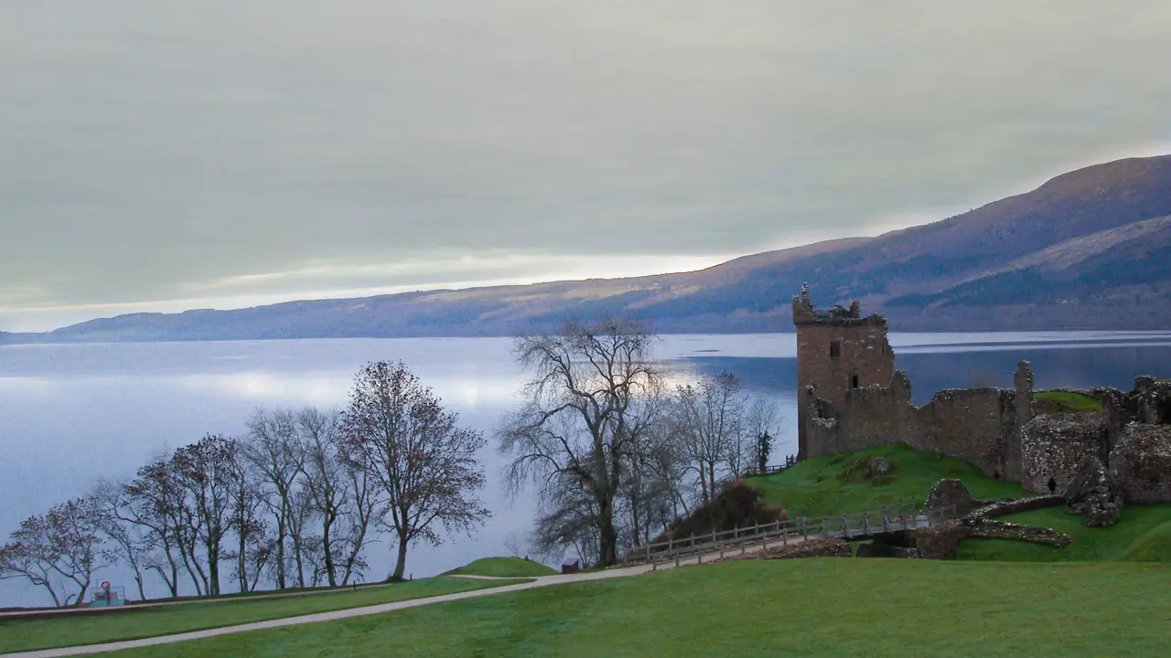  Urquhart Castle overlooking Loch Ness, with grass and leaveless trees in the forefront