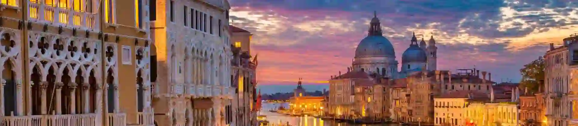 Sunset view of Venice featuring the iconic Salute Church beside a winding canal that stretches toward the open sea