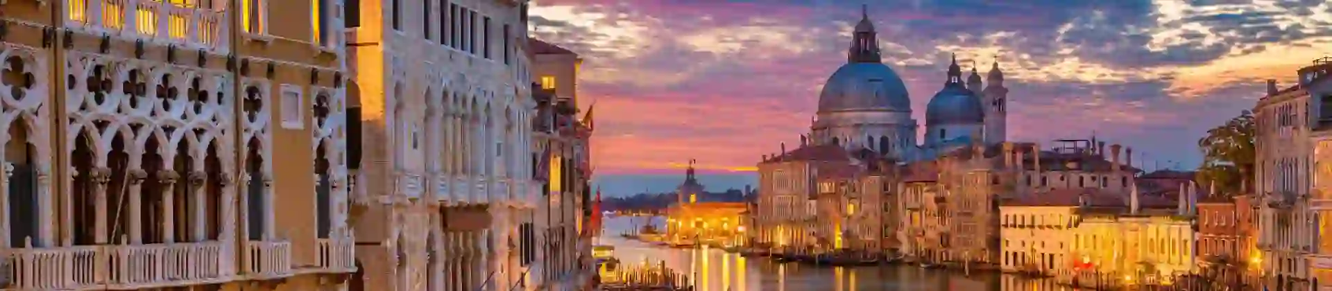 Sunset view of Venice featuring the iconic Salute Church beside a winding canal that stretches toward the open sea