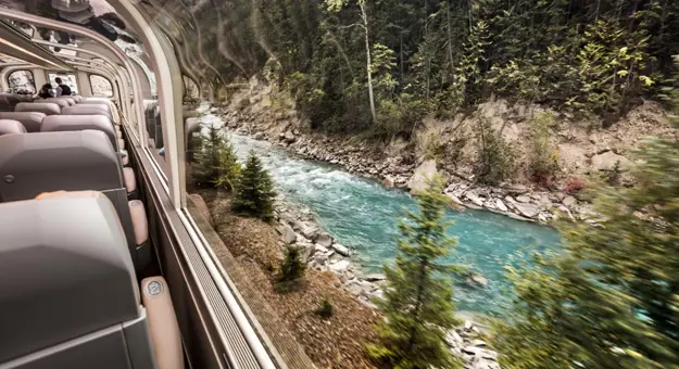 A Rocky Mountaineer train travelling through the Canadian landscape, with sleek carriages and large windows designed for scenic viewing