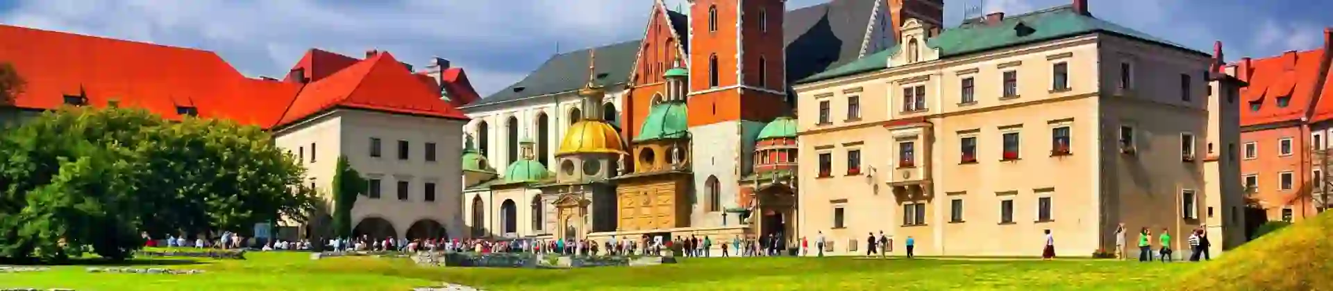 Wawel Castle in Kraków, Poland, showcasing its historic towers and red-brick walls beneath a cloudy blue sky