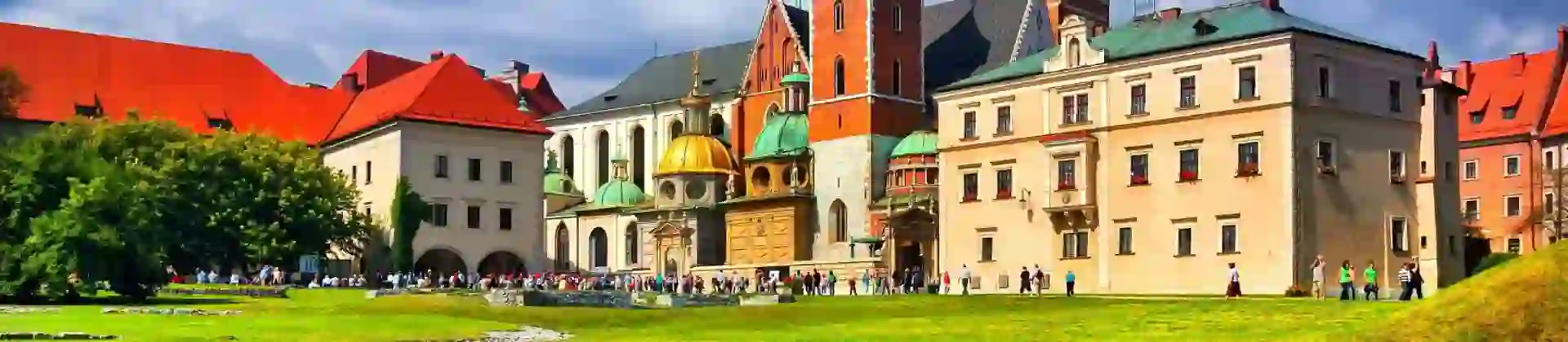 Wawel Castle in Kraków, Poland, showcasing its historic towers and red-brick walls beneath a cloudy blue sky
