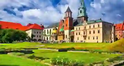 Wawel Castle in Kraków, Poland, showcasing its historic towers and red-brick walls beneath a cloudy blue sky