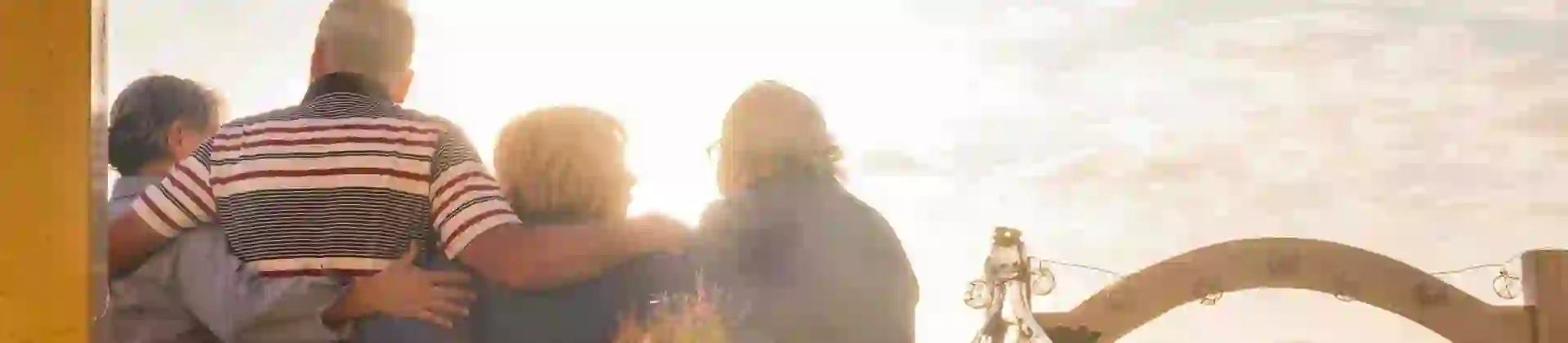 4 friends looking out over thier balcony with a table that has wine & food on it behind them