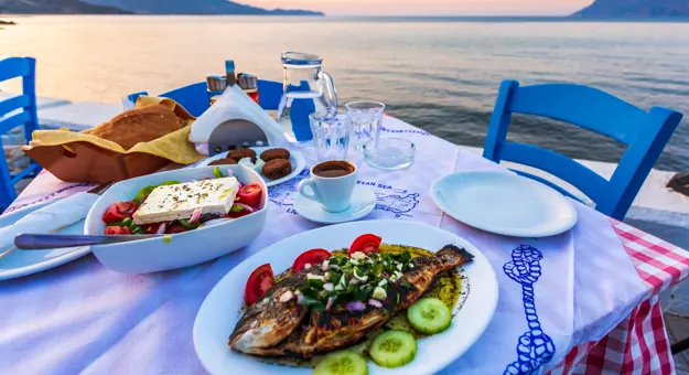 Dinner laid with traditional Cretan Dorada fish with Greek salad, with a view of the sea.