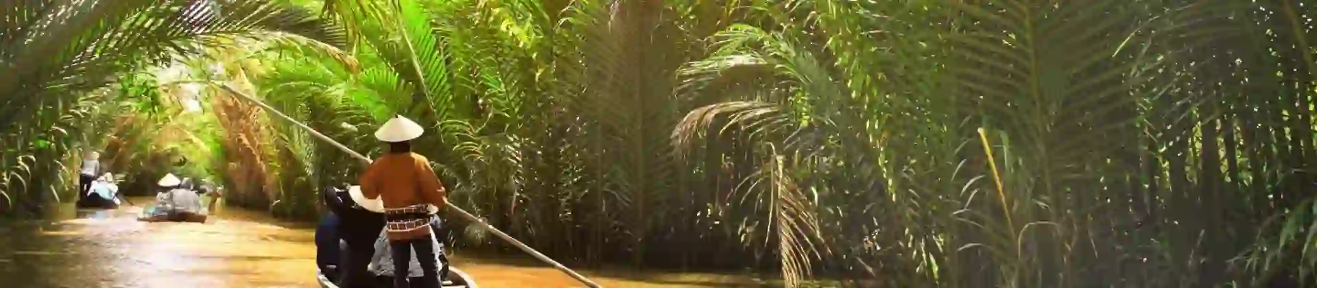 Small wooden boats glide through a palm-lined canal off the Mekong River in Thailand, with a person in a conical hat steering under filtered sunlight