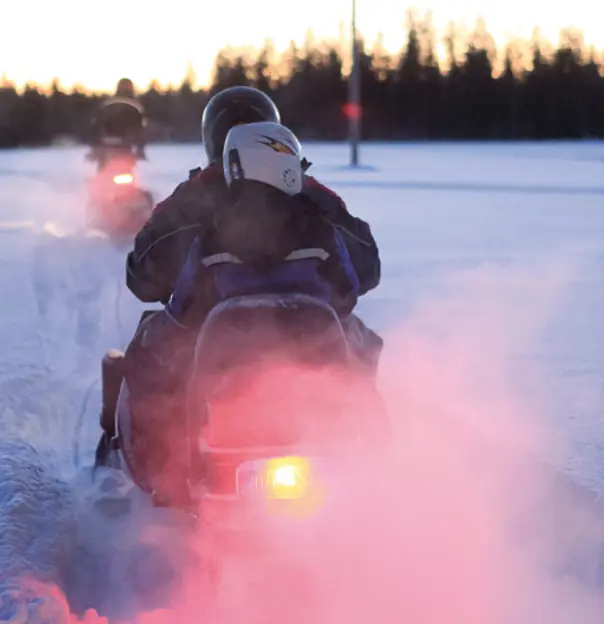 Image of a person riding a snowmobile from behind 