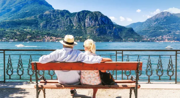 The back of a couple sat on a bench looking out to Lake Como