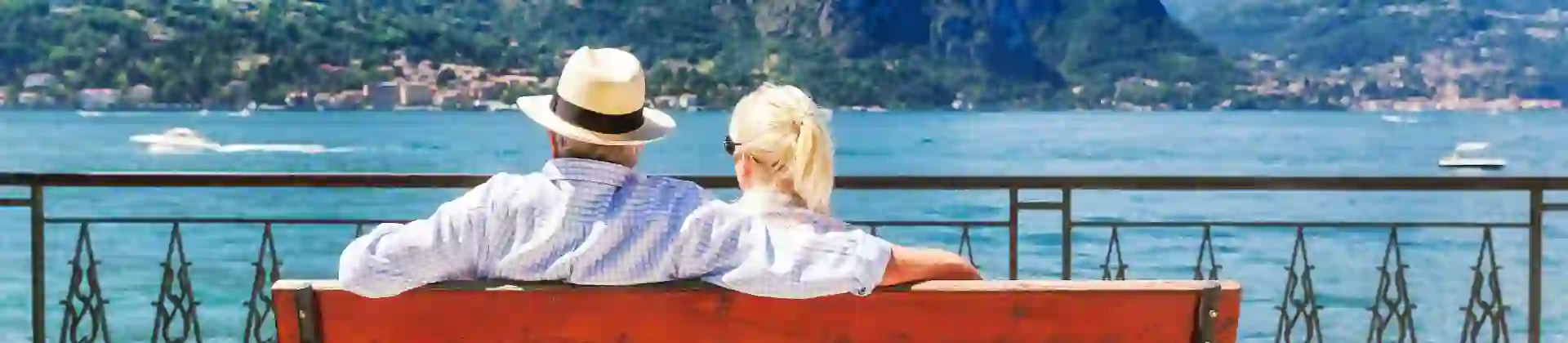The back of a couple sat on a bench looking out to Lake Como