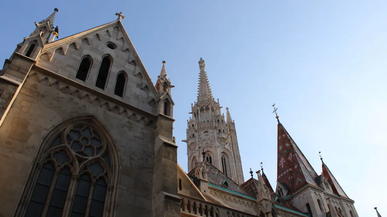 Low angle shot of Mátyás Church, with spiked turrets and triangular roofs.