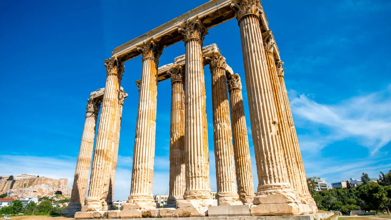 Low angle shot of temple ruins, with pillars. Blue sky behind