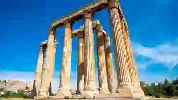 Low angle shot of temple ruins, with pillars. Blue sky behind