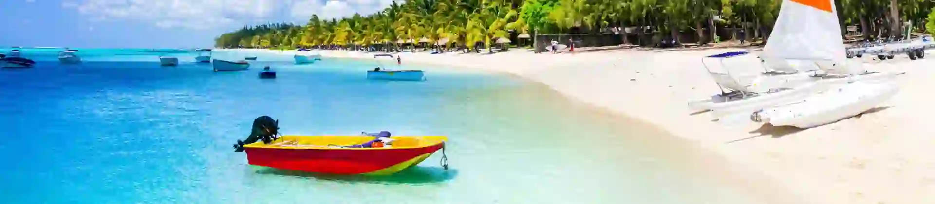 View of Mauritius featuring clear blue water, several boats floating on the sea, and a yacht on the sandy shore