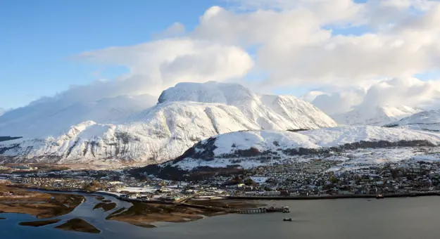 View of Fort William village with snowy Ben Nevis mountain behind 