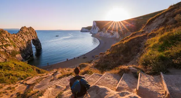 Person sitting on steps overlooking the beach on the Jurassic Coast Dorset 