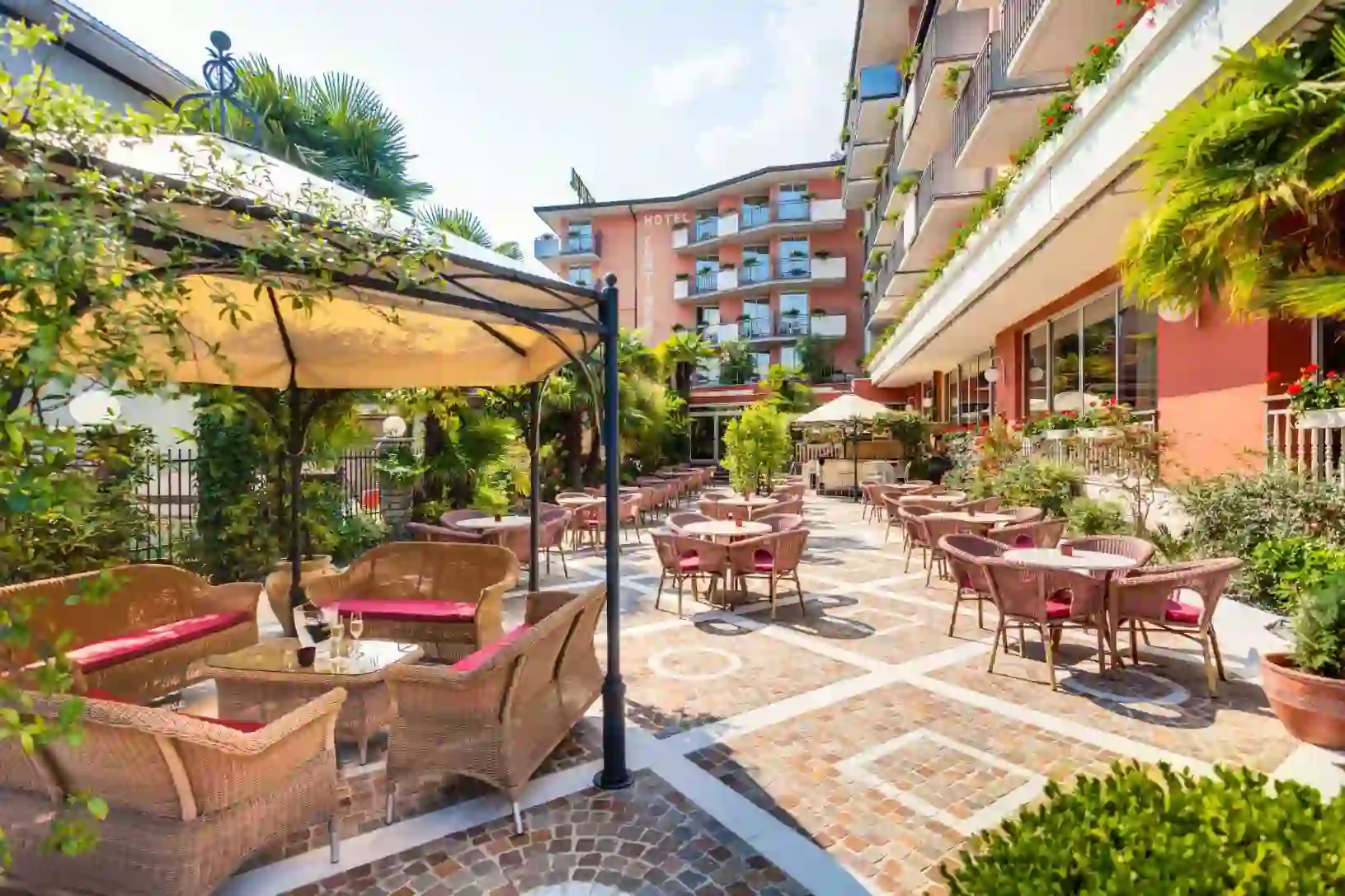 Sunny exterior dining area at Hotel Continental in Torbole, with wooden tables and chairs arranged for guests
