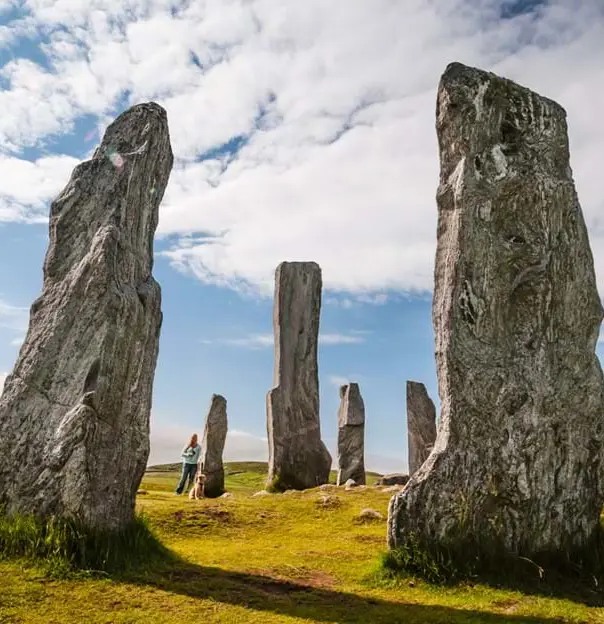 Low angle shot of the Callanish Standing Stones, with a woman standing next one