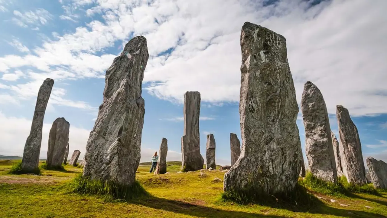 Low angle shot of the Callanish Standing Stones, with a woman standing next one