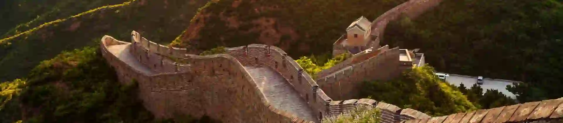 The Great Wall winding over green mountains at sunset, Beijing, China