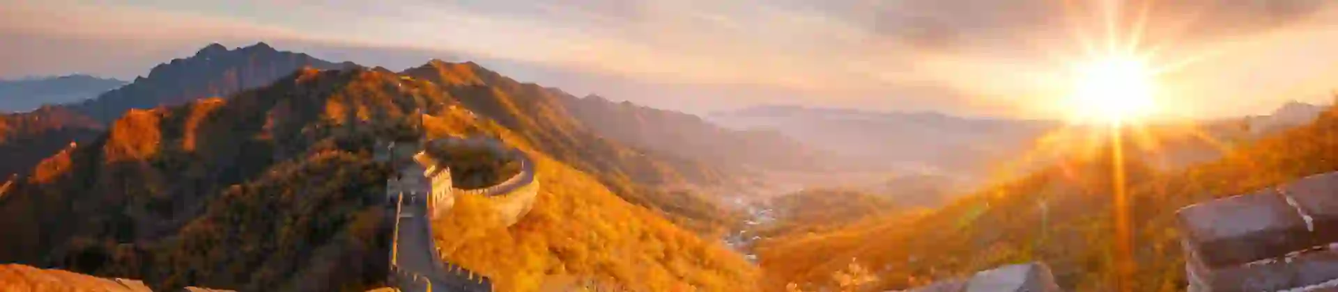 The Great Wall winding over mountain ridges, glowing in golden light at sunset, near Beijing, China