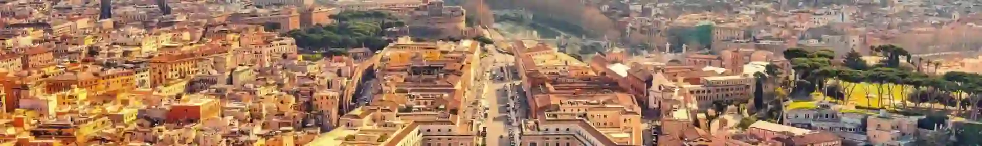 Aerial view of St. Peter’s Square in Vatican City, bathed in golden sunlight with Rome in the distance under a partly cloudy sky