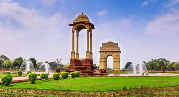 A view of India Gate and surrounding fountains and gardens in Delhi, India