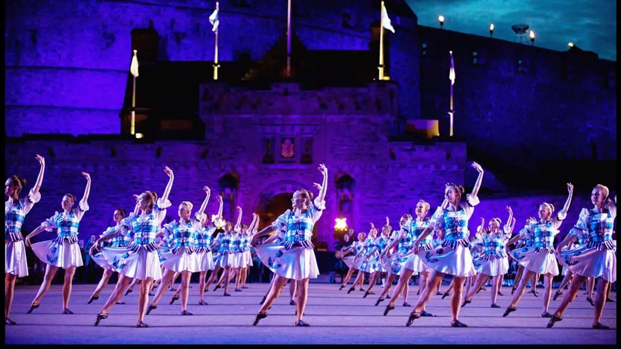 Highland female dancers dancing in unison outside Edinburgh Castle under purple lighting