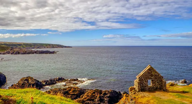 View of Moray Firth inlet, with grass and ruins of a building in the forefront