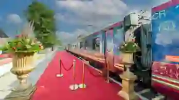 Exterior view of the Deccan Odyssey train at the platform, with a red carpet and gold barriers by the entrance