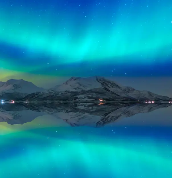 Northern lights (Aurora borealis) in the sky over Tromso, Norway - Aurora reflection on the sea on the background Norwegian fjord - Winter season.