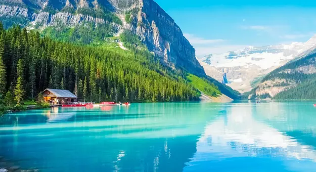 Turquoise waters of Lake Louise surrounded by forested slopes and snow-capped mountains