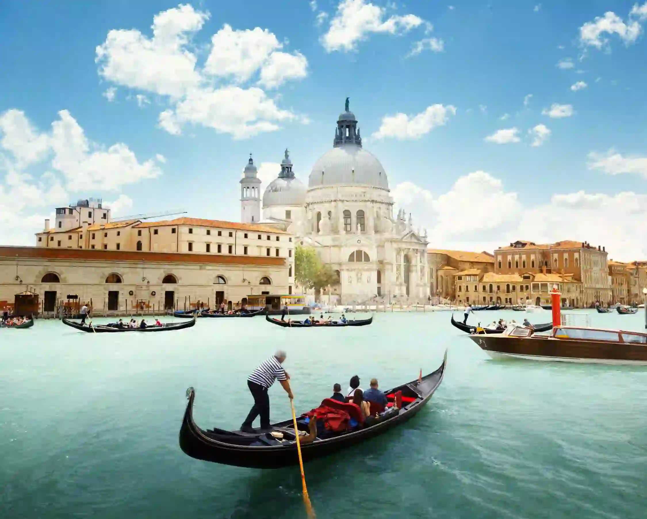 View of gondola boats travelling on the water and the Salute Church in Venice, Italy