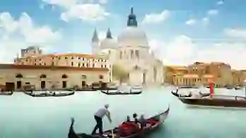 View of gondola boats travelling on the water and the Salute Church in Venice, Italy