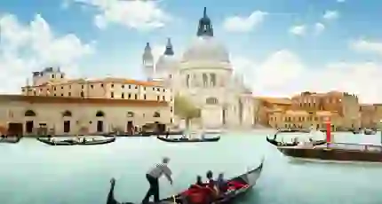 View of gondola boats travelling on the water and the Salute Church in Venice, Italy