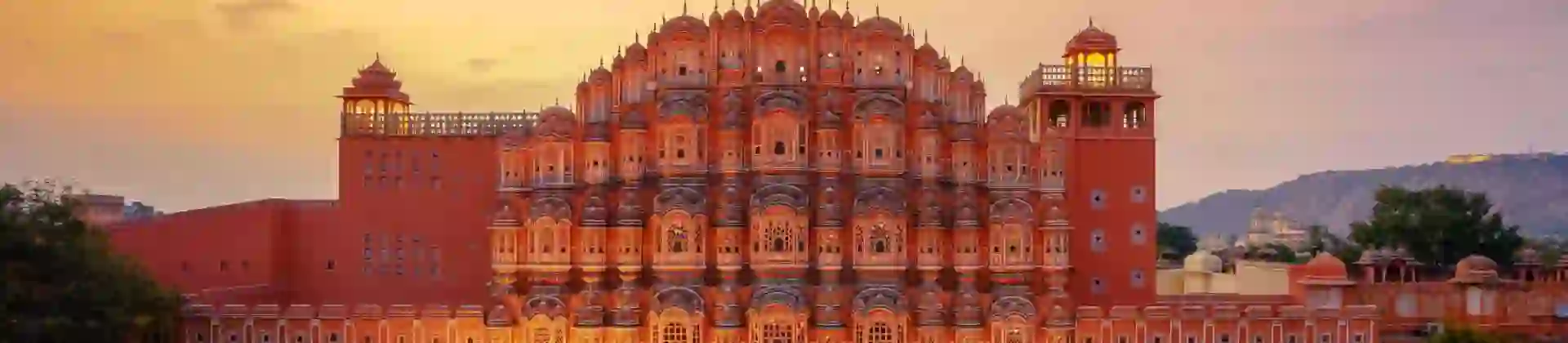 The Palace of the Winds in Jaipur illuminated at sunset, its ornate pink façade overlooking the street below
