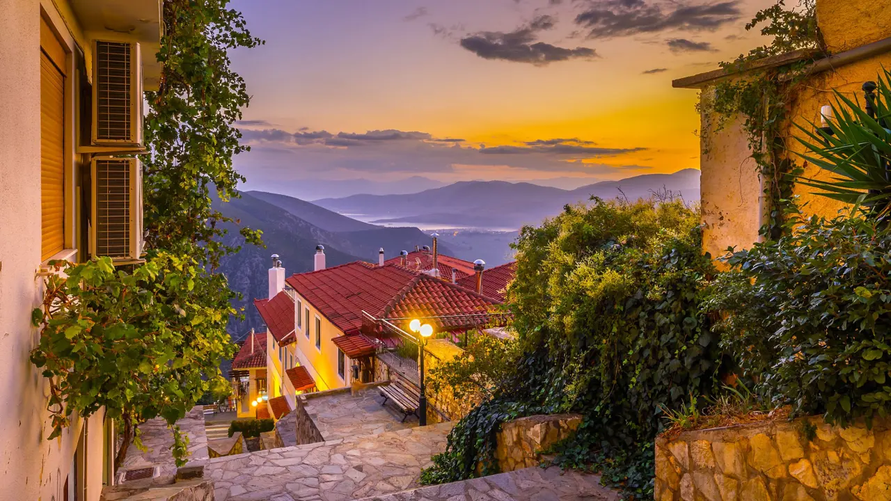 View from a village in the mountains, looking out on the landscape with sunset and silhouette of mountains. Steps and buildings in the forefront