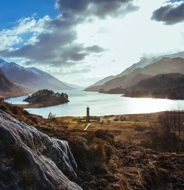 Zoomed out image of Glenfinnan Monument, with the view of Loch Shiel and the surrounding mountains