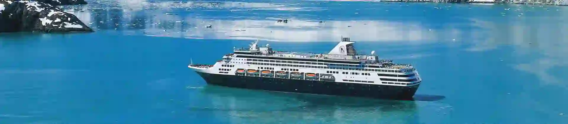 The MS Koningsdam cruise ship sailing through Glacier Bay, surrounded by calm icy waters and dramatic snow-capped mountains