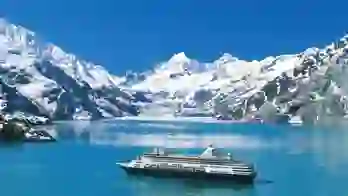The MS Koningsdam cruise ship sailing through Glacier Bay, surrounded by calm icy waters and dramatic snow-capped mountains