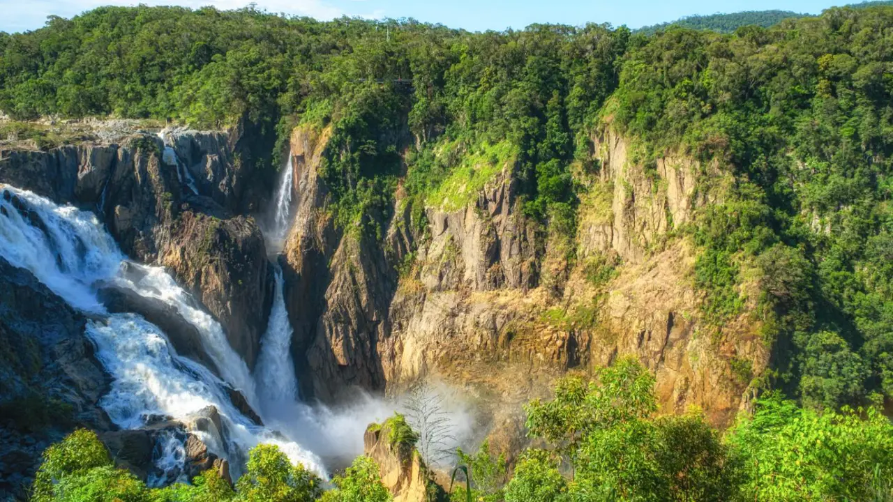 A lush rainforest gorge in Barron Gorge National Park near Kuranda, Queensland, showing towering greenery, a steep ravine and misty atmosphere.