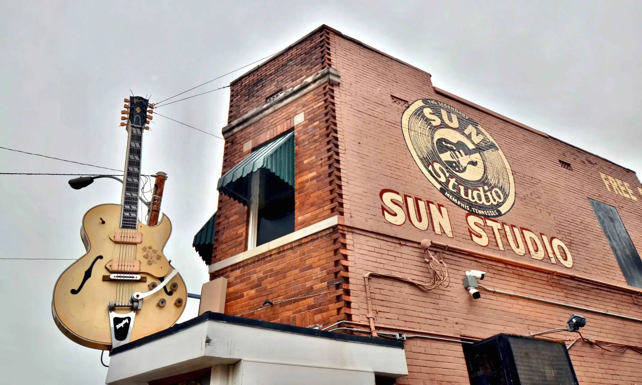 Sun Studio building with orange brick exterior, a large guitar-shaped sign outside, and the words “Sun Studio” painted in yellow on the side of the building