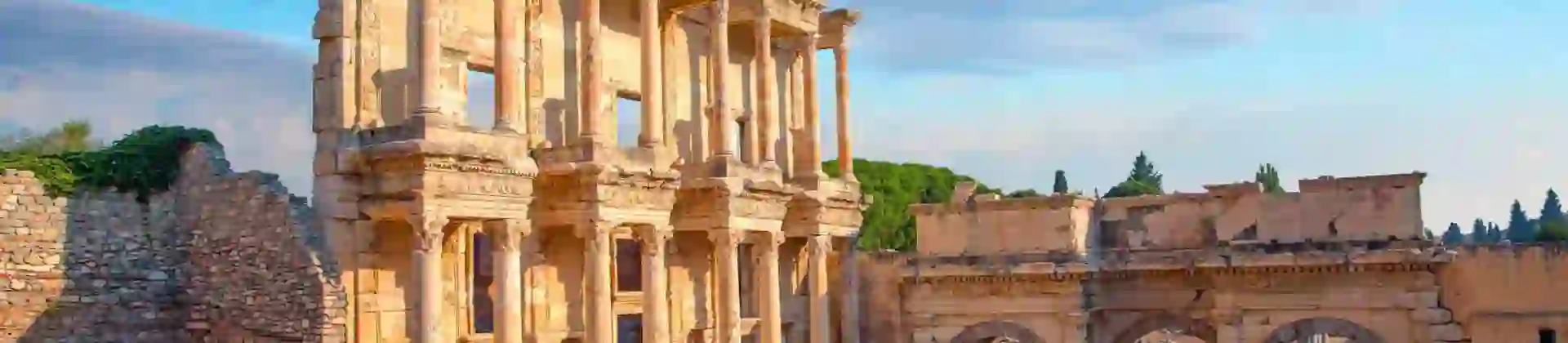 Ancient ruins of the Library of Celsus in Ephesus, Turkey, with a clear sky and warm sunlight highlighting the detailed stone architecture